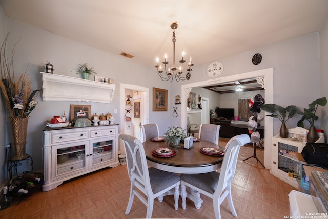 dining area with ceiling fan with notable chandelier and parquet flooring