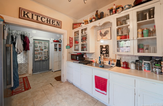 kitchen featuring sink, white cabinetry, tasteful backsplash, and light tile patterned floors