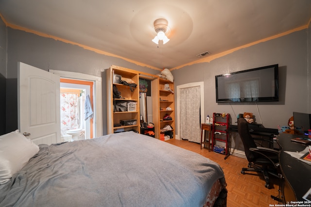 bedroom with connected bathroom, light parquet flooring, and ceiling fan