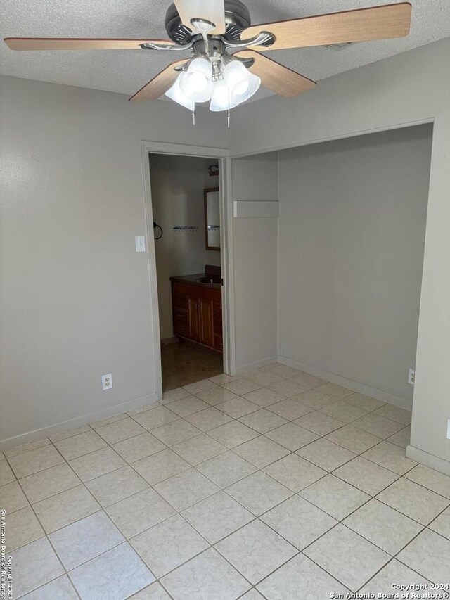 unfurnished room featuring ceiling fan, sink, a textured ceiling, and light tile patterned floors