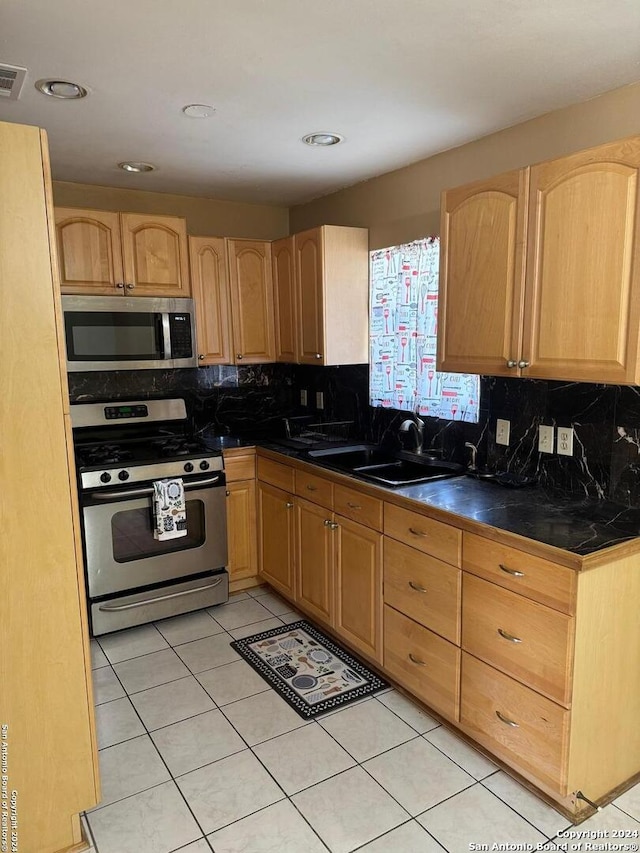 kitchen with light tile patterned flooring, decorative backsplash, stainless steel appliances, and sink