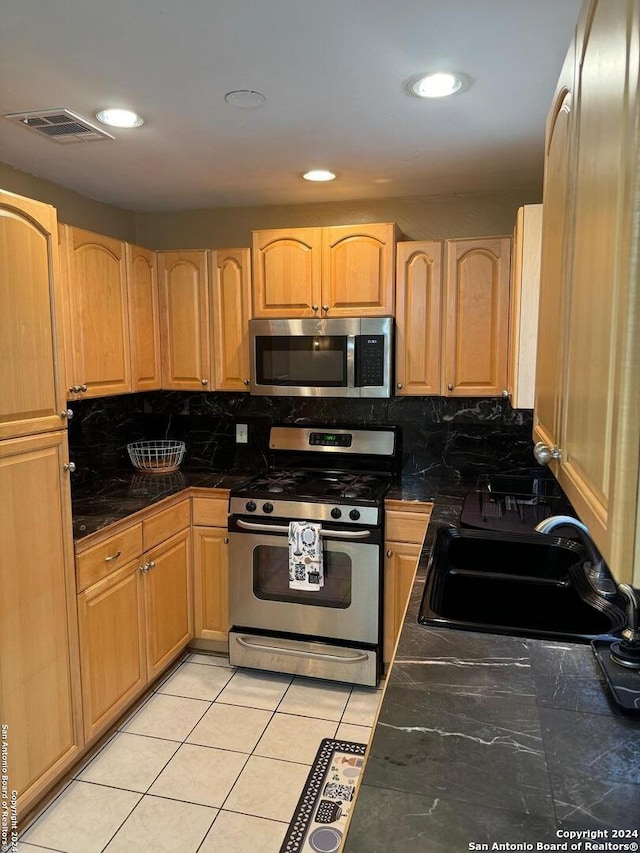 kitchen featuring tasteful backsplash, appliances with stainless steel finishes, sink, and light tile patterned floors