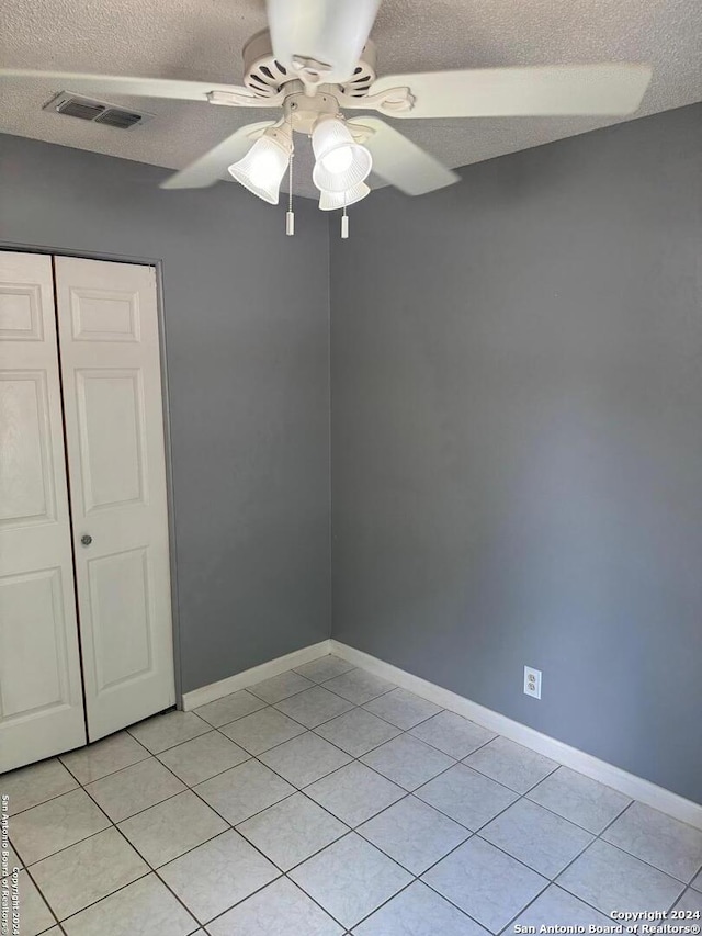 interior space featuring light tile patterned flooring, a textured ceiling, and ceiling fan