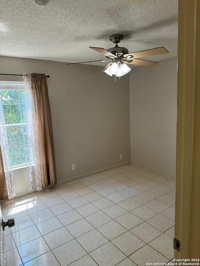 tiled empty room featuring ceiling fan and a textured ceiling