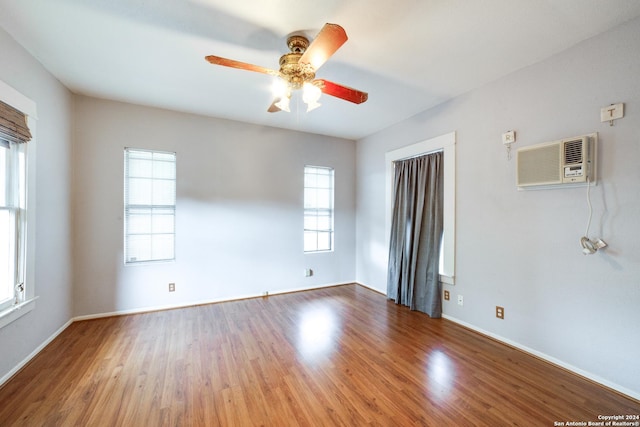 empty room with wood-type flooring, ceiling fan, and a wall unit AC