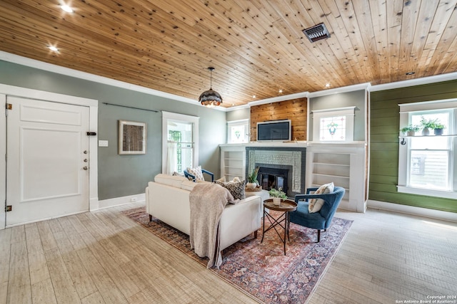 living room with wood ceiling, crown molding, a brick fireplace, and light wood-type flooring