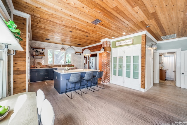 kitchen with wood ceiling, a kitchen island, stainless steel fridge, and decorative light fixtures