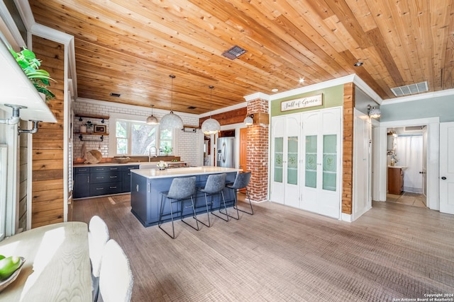 kitchen with sink, wood ceiling, crown molding, hanging light fixtures, and a kitchen breakfast bar