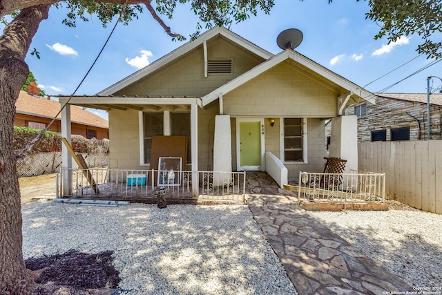 view of front facade with covered porch, concrete block siding, and fence