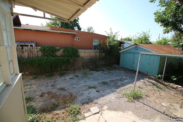 view of yard with a storage shed, fence, and an outbuilding