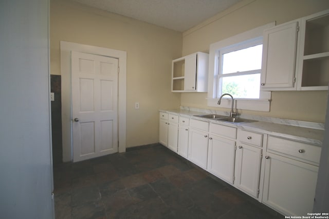 kitchen featuring sink, white cabinetry, and dark tile patterned floors