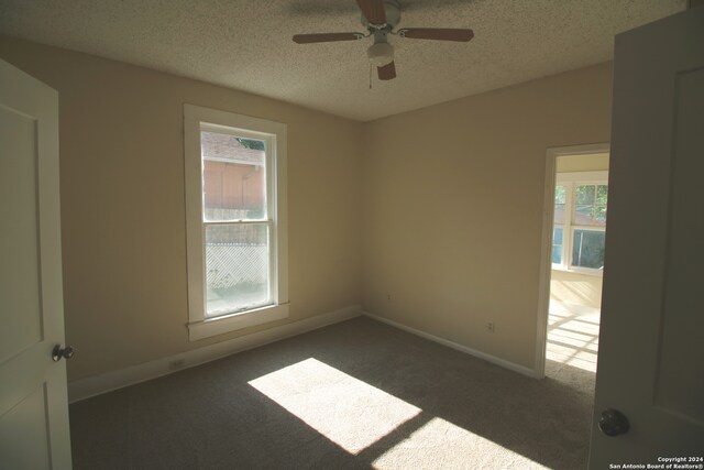 carpeted spare room featuring a textured ceiling and ceiling fan