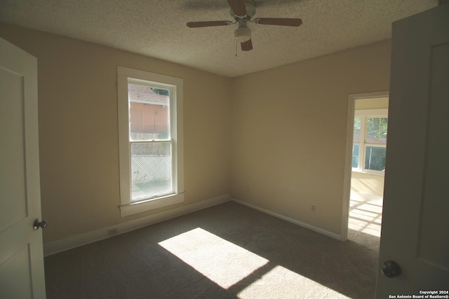 spare room featuring a ceiling fan, dark carpet, a textured ceiling, and baseboards