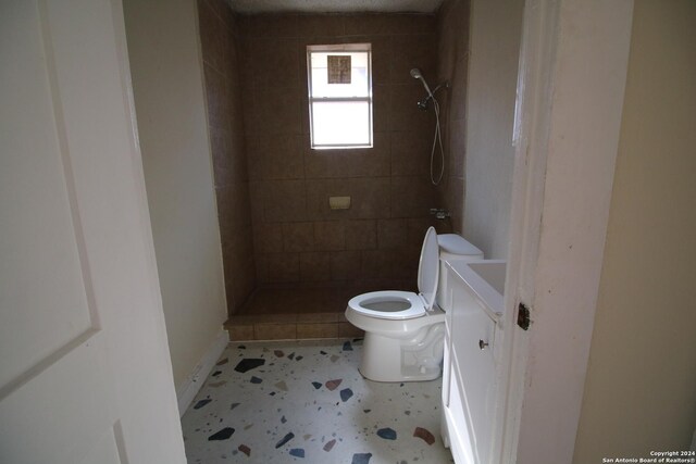 bathroom featuring vanity, toilet, a tile shower, and tile patterned flooring