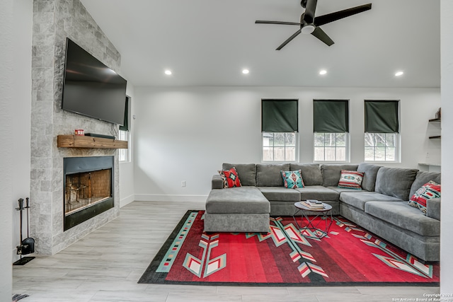 living room with a tiled fireplace, hardwood / wood-style floors, and ceiling fan