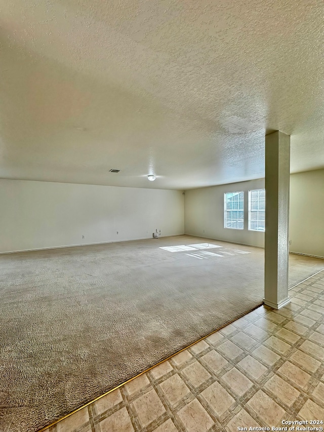 basement featuring light carpet and a textured ceiling