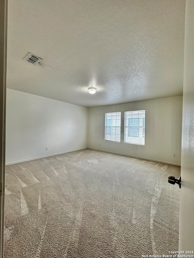 carpeted empty room featuring a textured ceiling