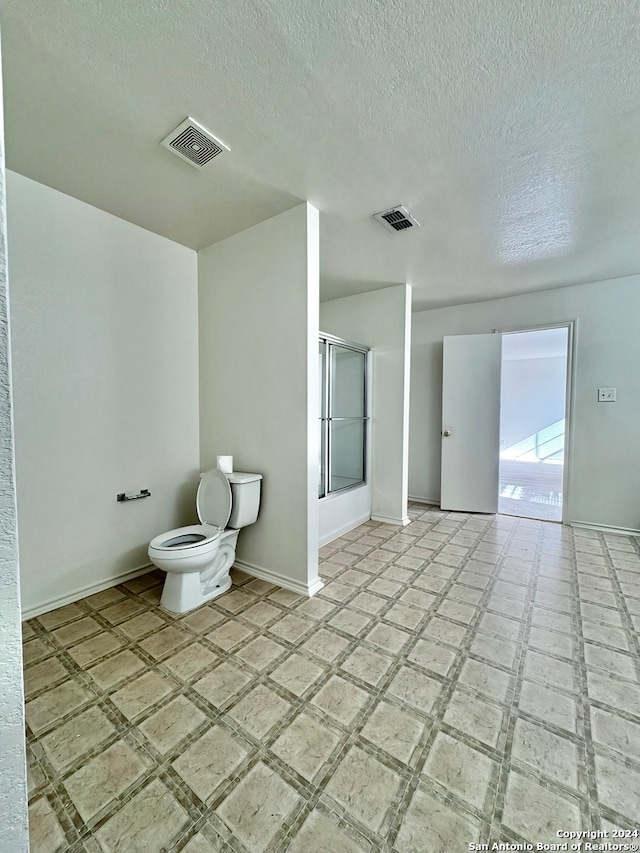 bathroom featuring tile patterned floors, a textured ceiling, and toilet