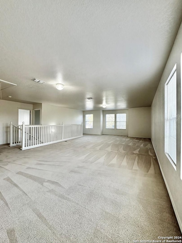 carpeted empty room with a textured ceiling