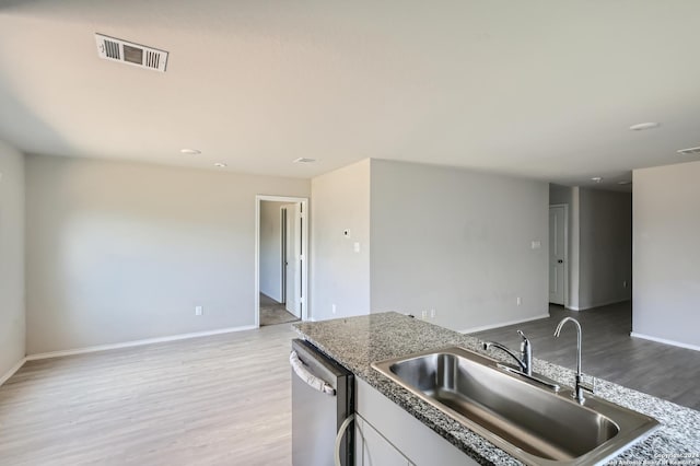 kitchen featuring stainless steel dishwasher, sink, light hardwood / wood-style flooring, and white cabinets