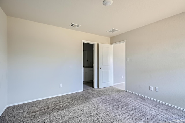 unfurnished bedroom featuring ensuite bath and carpet