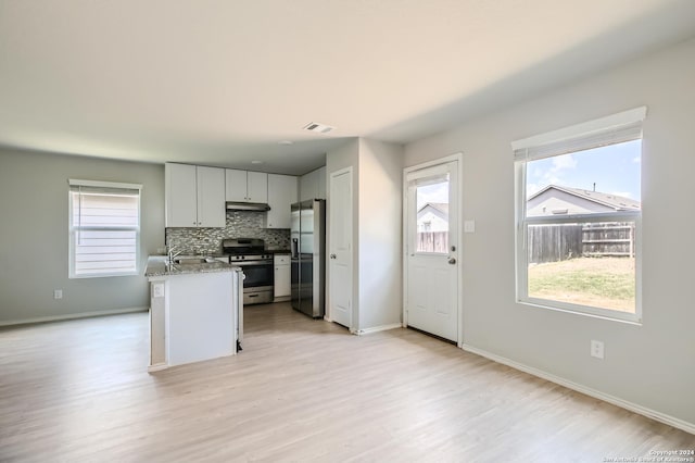 kitchen featuring light stone counters, backsplash, a wealth of natural light, and stainless steel appliances