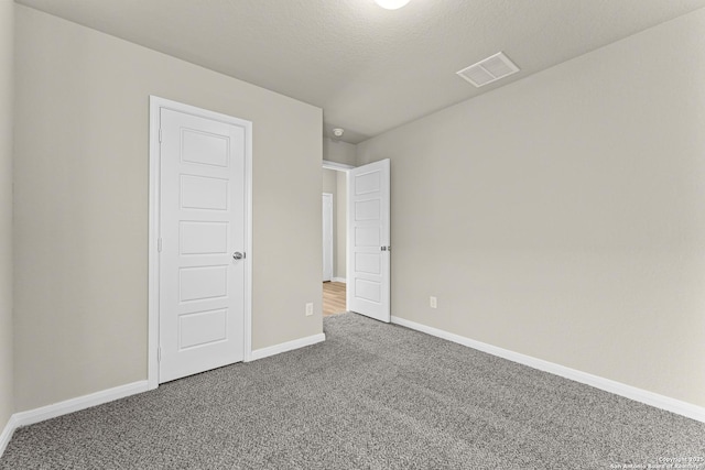 empty room featuring carpet and a textured ceiling