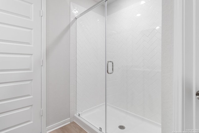 bathroom with wood-type flooring and a shower with door