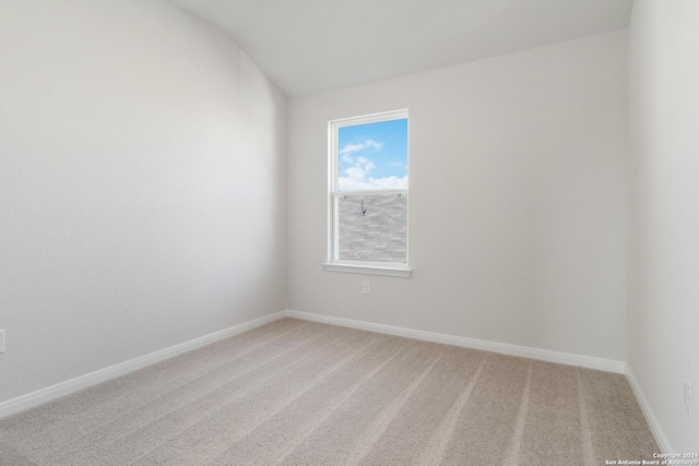 carpeted spare room featuring lofted ceiling