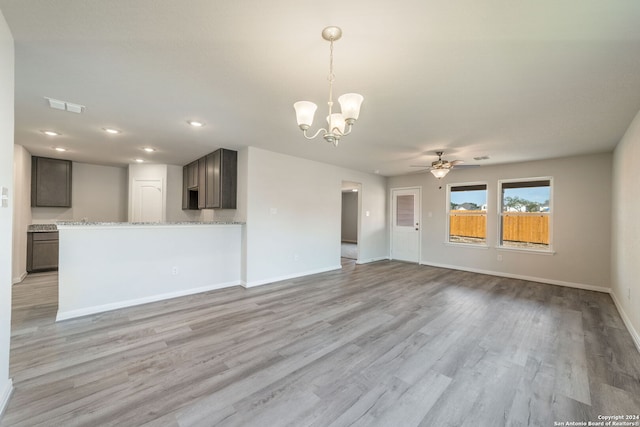 unfurnished living room featuring ceiling fan with notable chandelier and light wood-type flooring