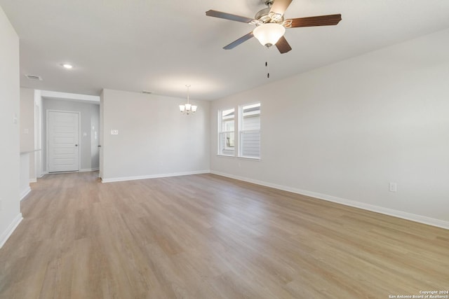 spare room featuring ceiling fan with notable chandelier and light wood-type flooring