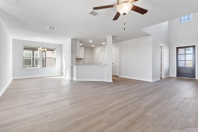 unfurnished living room featuring sink, ceiling fan with notable chandelier, and light hardwood / wood-style floors