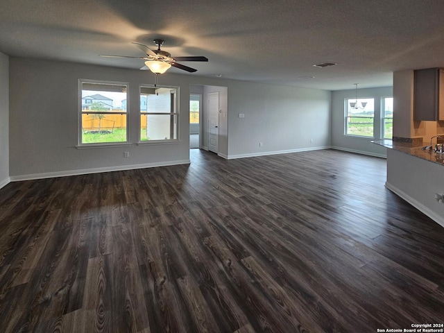 unfurnished living room with dark hardwood / wood-style floors, ceiling fan, and a textured ceiling