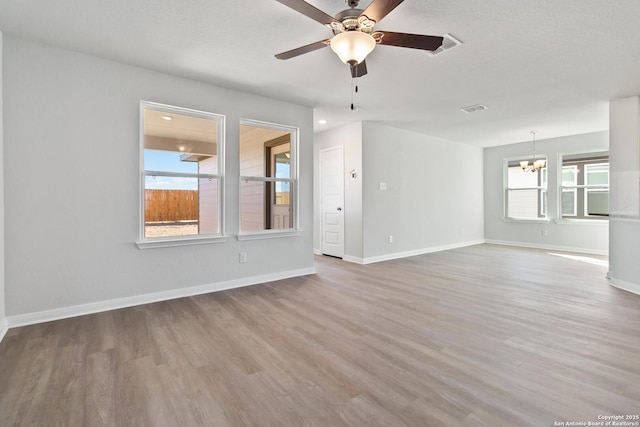 empty room with wood-type flooring and ceiling fan with notable chandelier