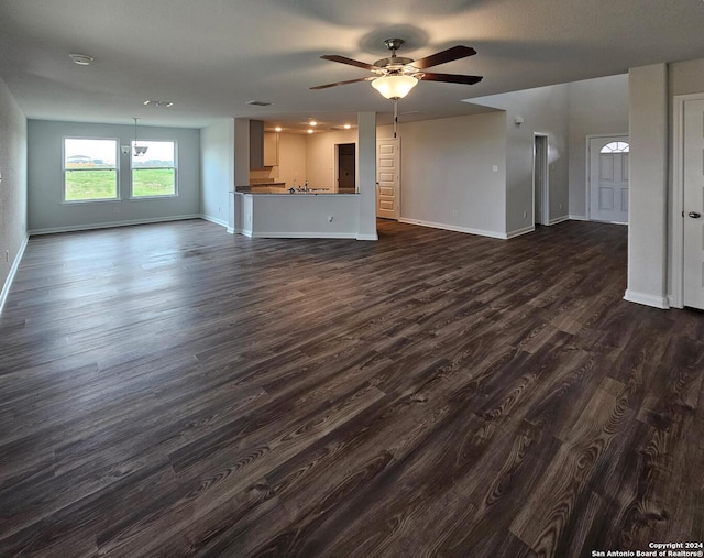 unfurnished living room featuring dark wood-type flooring and ceiling fan