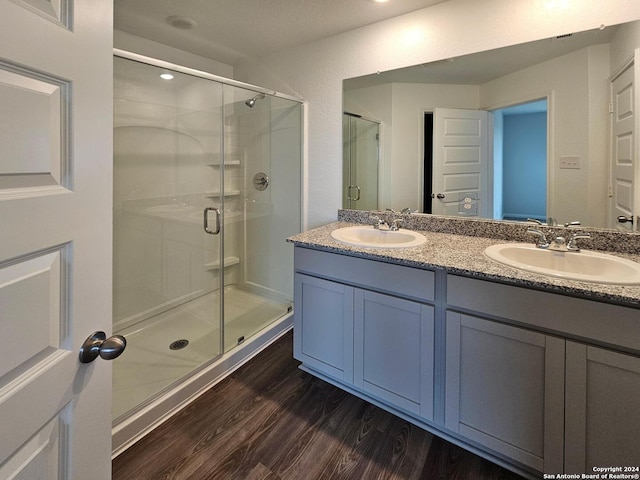 bathroom featuring a shower with shower door, wood-type flooring, and double vanity