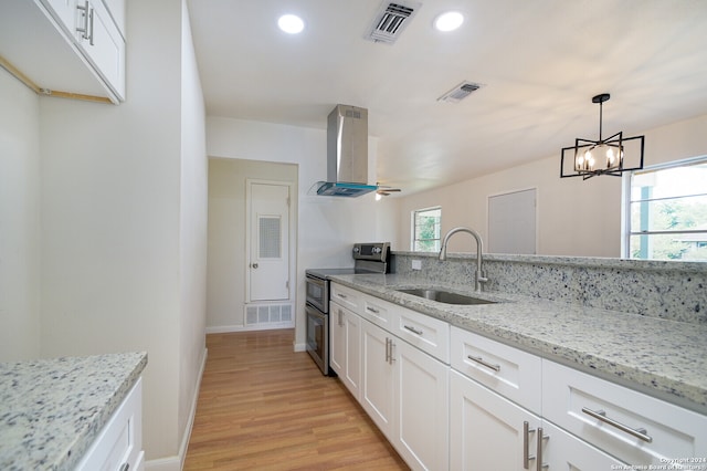 kitchen featuring ventilation hood, sink, light stone counters, and range with two ovens