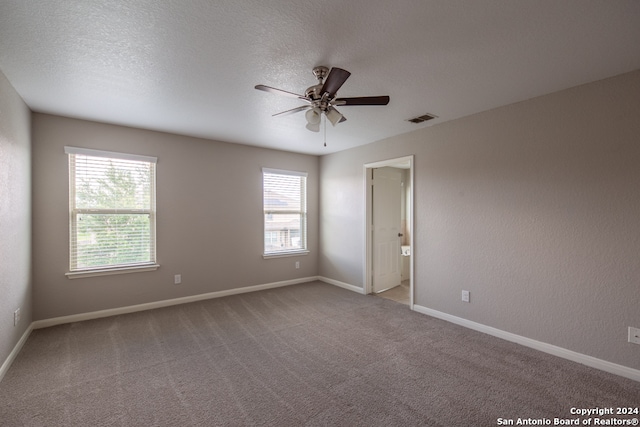 carpeted spare room with a textured ceiling and ceiling fan