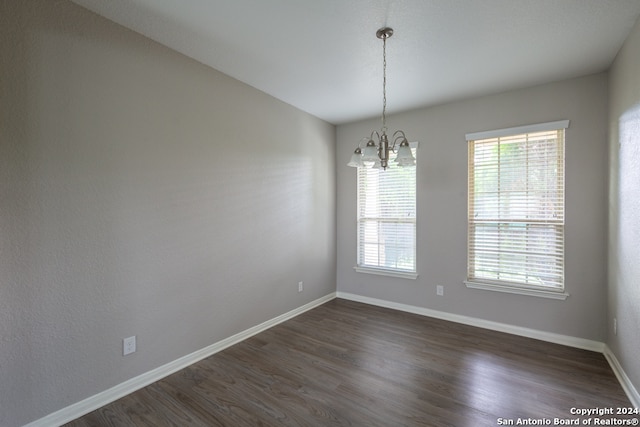 unfurnished room featuring dark hardwood / wood-style flooring, a healthy amount of sunlight, and a chandelier