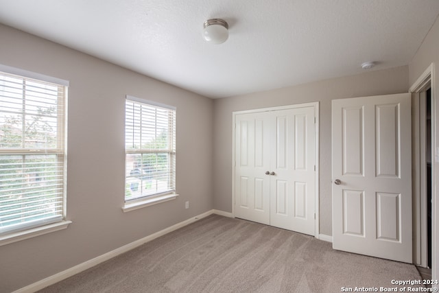 unfurnished bedroom featuring light carpet and a closet