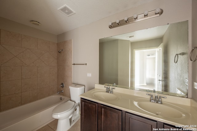 full bathroom featuring double sink vanity, tiled shower / bath combo, toilet, a textured ceiling, and tile patterned flooring