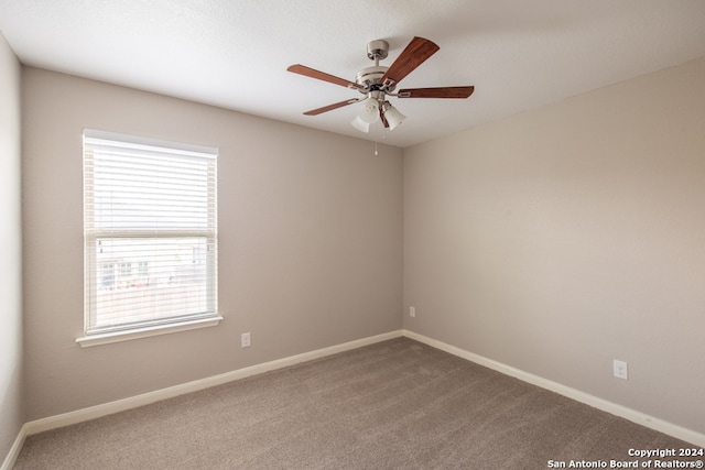 spare room featuring carpet, a wealth of natural light, and ceiling fan