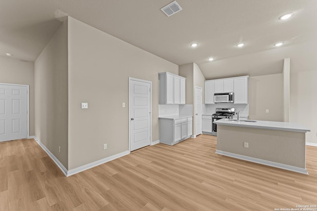 kitchen featuring stainless steel appliances, white cabinets, light wood-type flooring, and kitchen peninsula