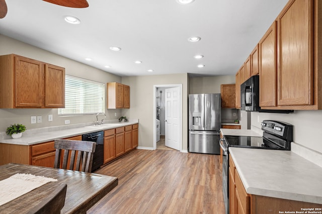 kitchen featuring sink, black appliances, and light hardwood / wood-style floors