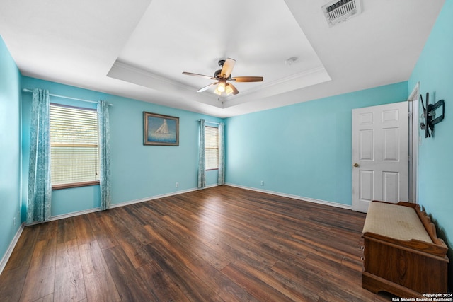 empty room with hardwood / wood-style flooring, a raised ceiling, and ceiling fan