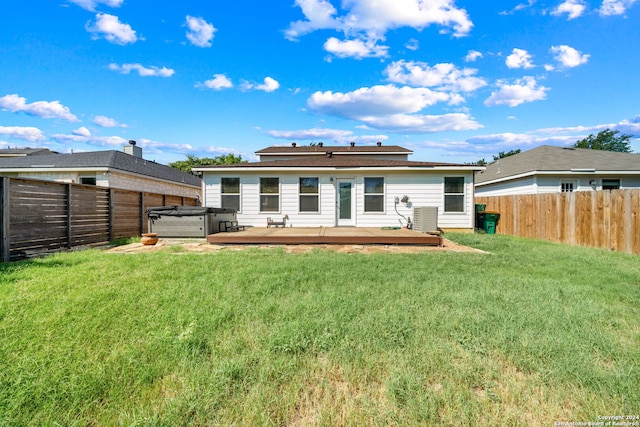 rear view of house featuring a deck, central air condition unit, a hot tub, and a yard