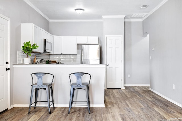 kitchen with stainless steel fridge, a breakfast bar area, white cabinetry, backsplash, and light wood-type flooring