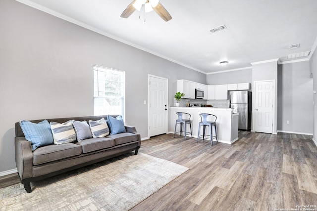 living room featuring ornamental molding, ceiling fan, and light hardwood / wood-style floors