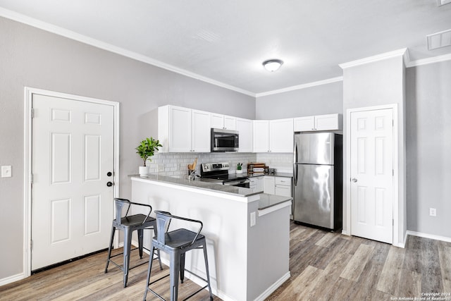 kitchen featuring appliances with stainless steel finishes, kitchen peninsula, and light hardwood / wood-style flooring