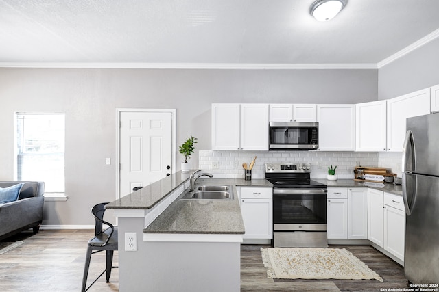 kitchen featuring appliances with stainless steel finishes, hardwood / wood-style flooring, a kitchen breakfast bar, and backsplash